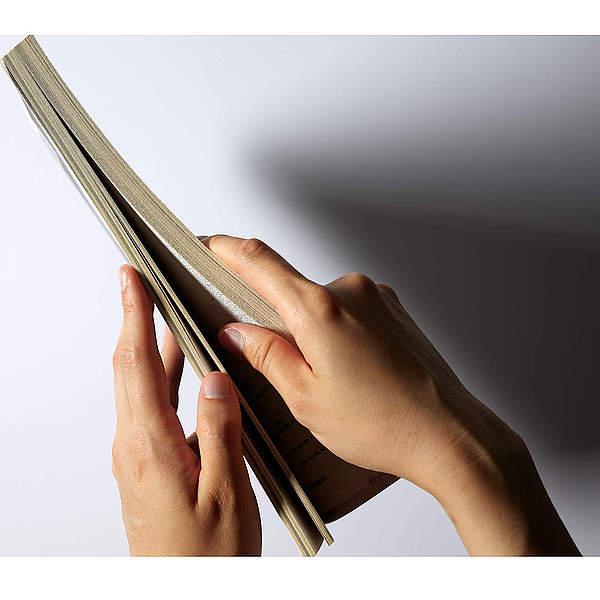 Hände öffnen ein Buch auf einem weißen Hintergrund.